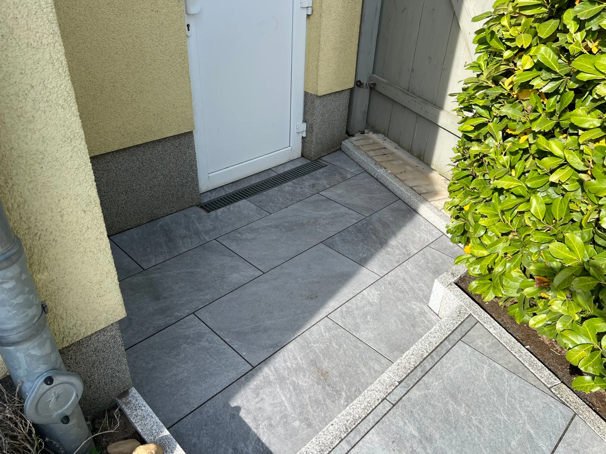Nebeneingang mit Entwässerungsrinne und diagonal verlegten Platten