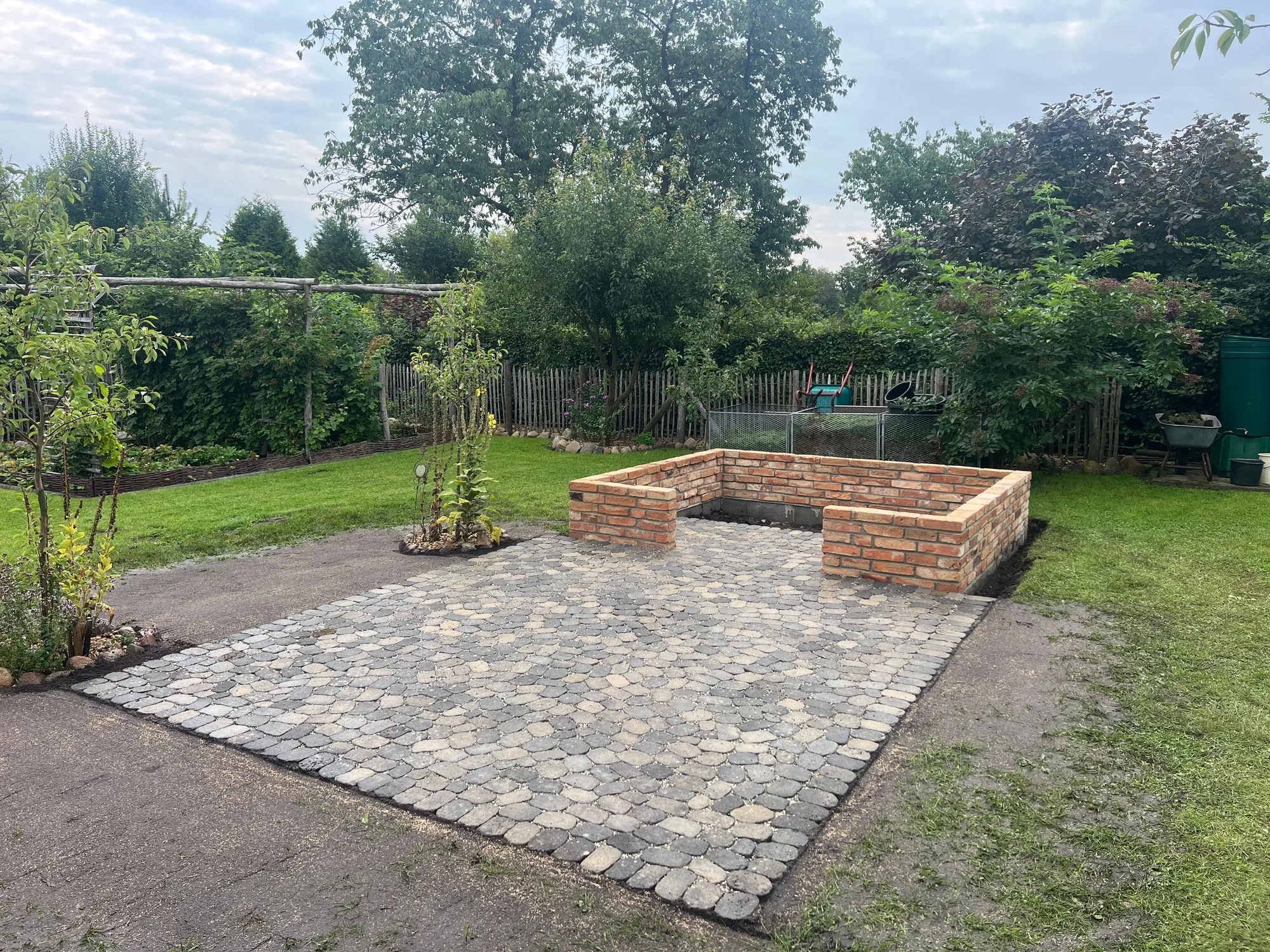Sitzplatz aus Natursteinpflaster mit Ziegel-Hochbeet